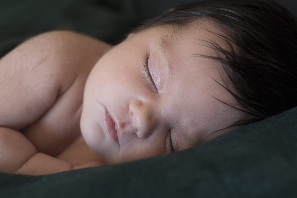 bebé recién nacido dormido en primer plano sobre manta verde oscura