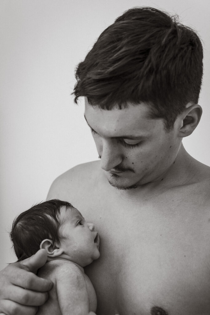 padre sosteniendo a su bebé recién nacido con gesto cariñoso