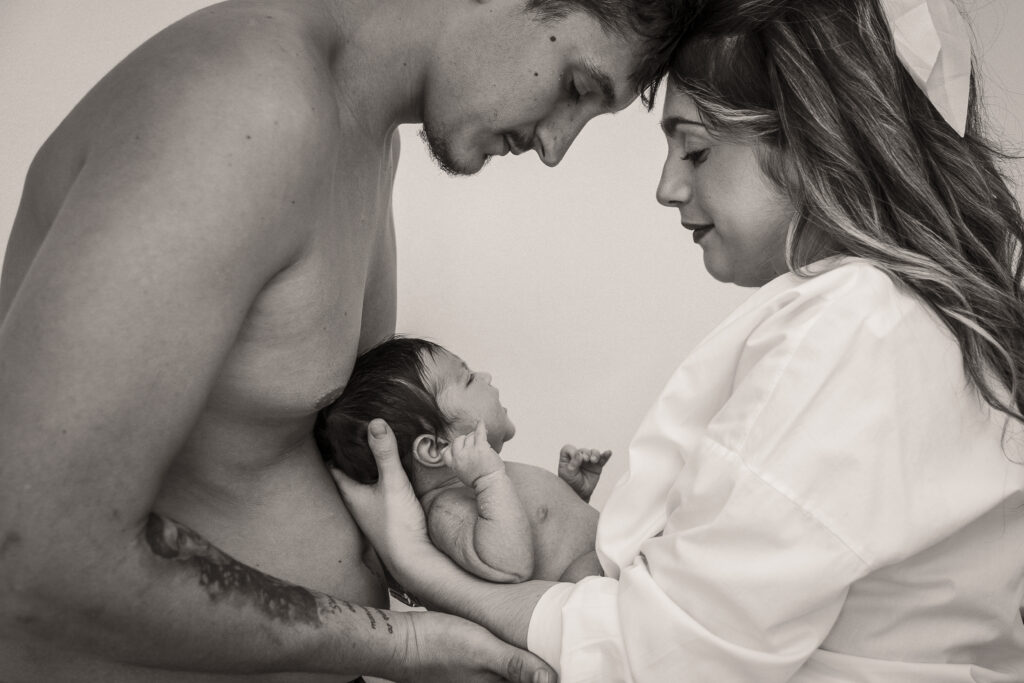padres sonrientes mirando a su bebé recién nacido en brazos