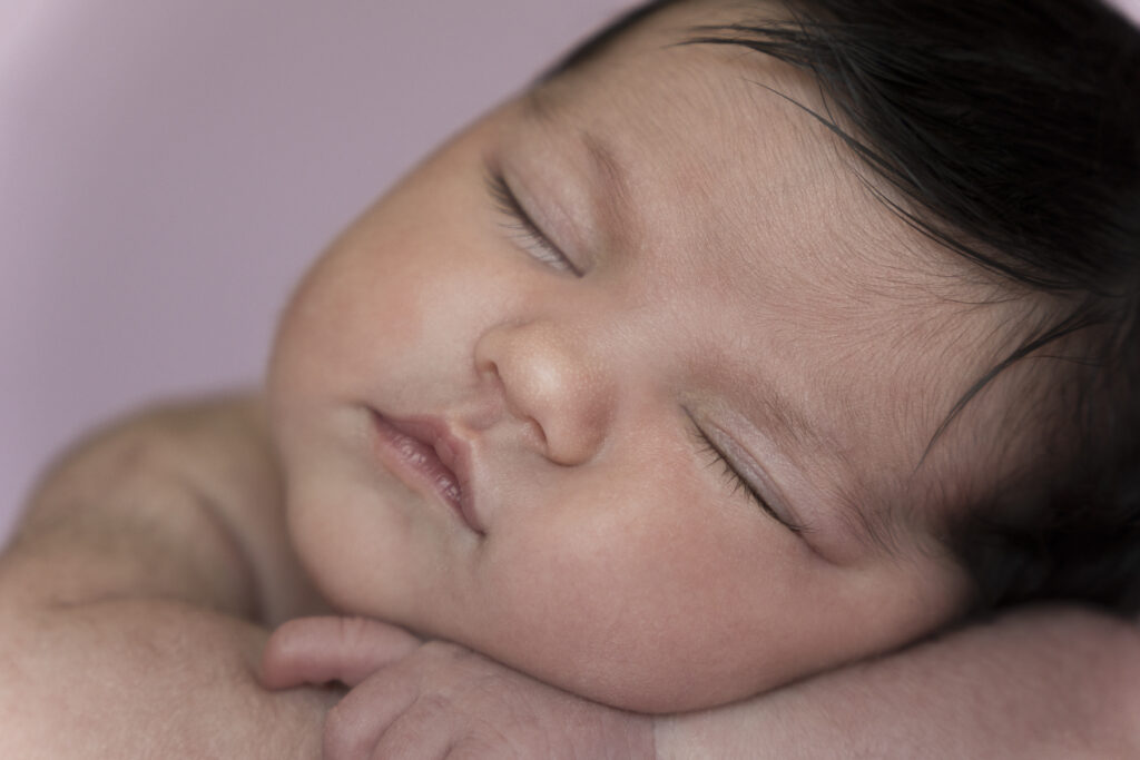 primer plano de bebé recién nacido dormido sobre fondo rosa