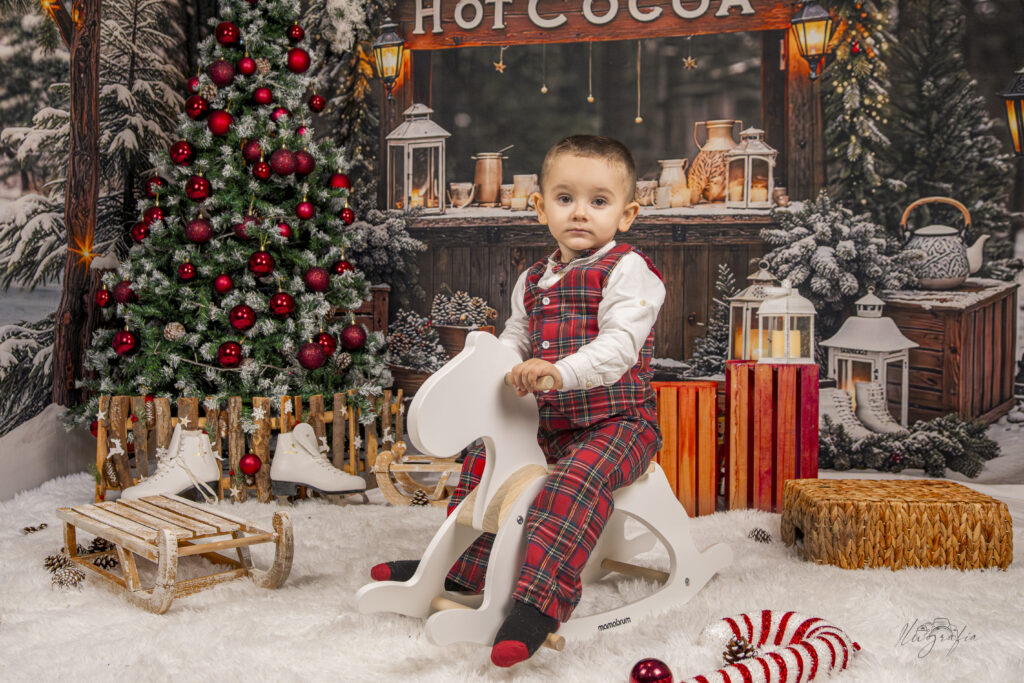 Niño pequeño disfrutando de sesión de Navidad en estudio con reno decorativo en Dos Hermanas