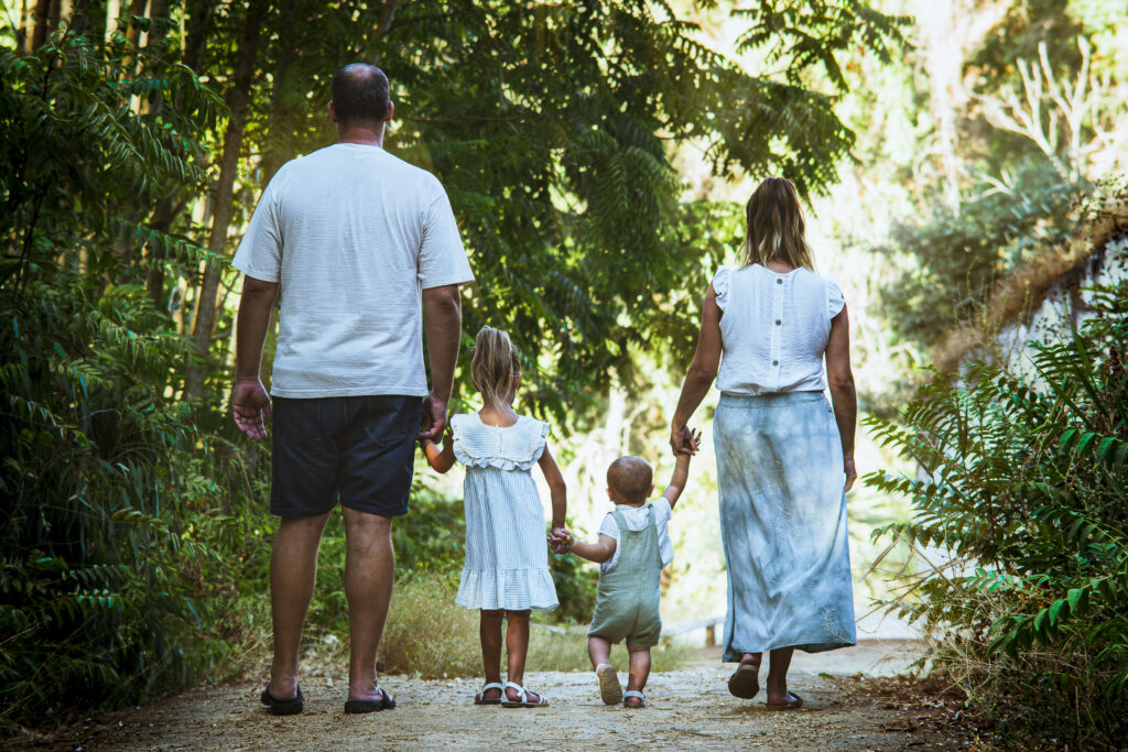 Familia caminando de la mano en un entorno natural durante una sesión familiar
