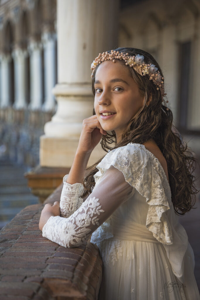 Niña de comunión con vestido blanco y corona de flores en exteriores
