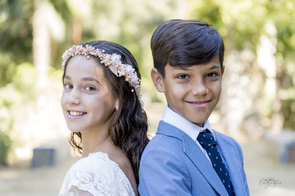 Niña y niño de comunión posando juntos en exteriores