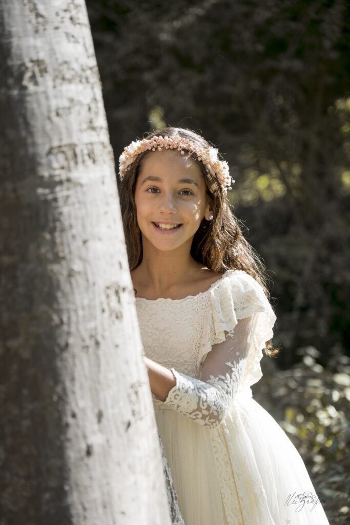 Retrato de niña de comunión apoyada en un árbol