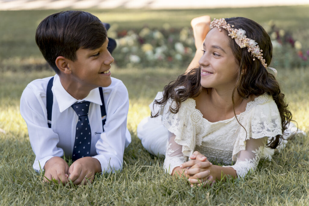 Niño y niña de comunión tumbados sobre el césped