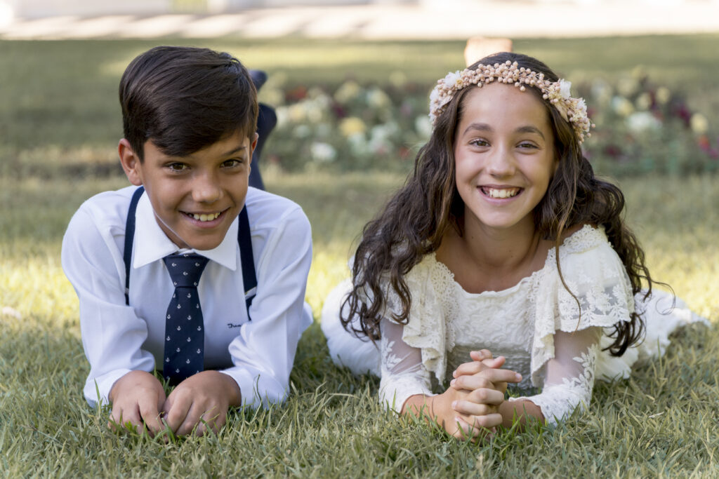Niño y niña de comunión sonriendo en el suelo