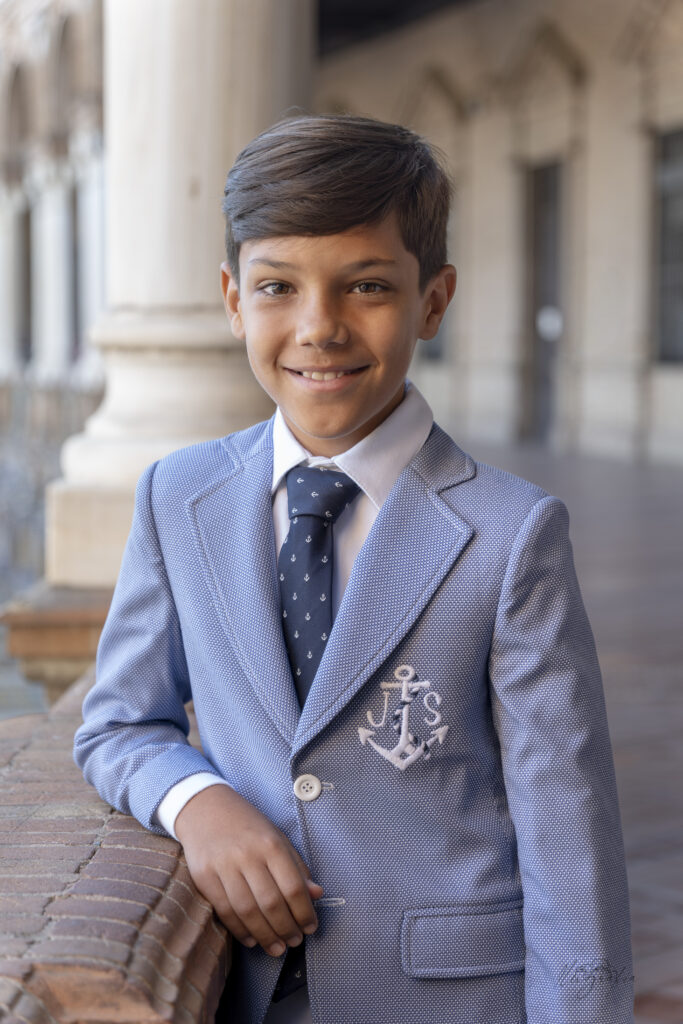 Niño de comunión con traje azul claro en retrato exterior