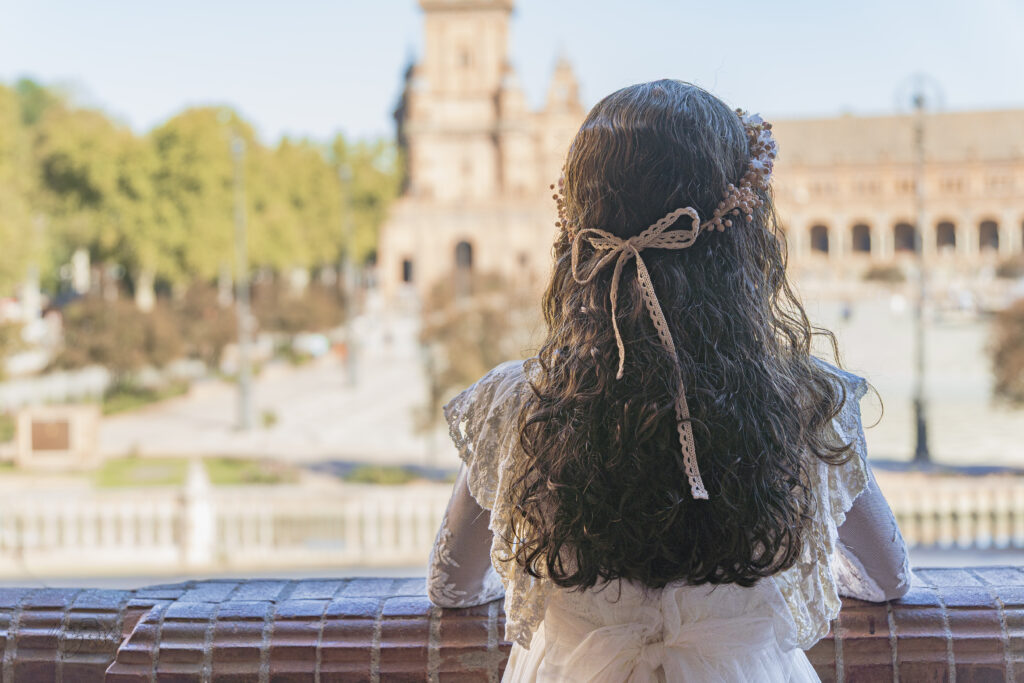 Niña de comunión de espaldas con vestido y paisaje urbano