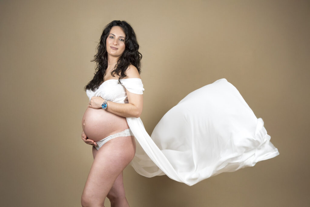 Mujer embarazada con tela ondeando en el aire.