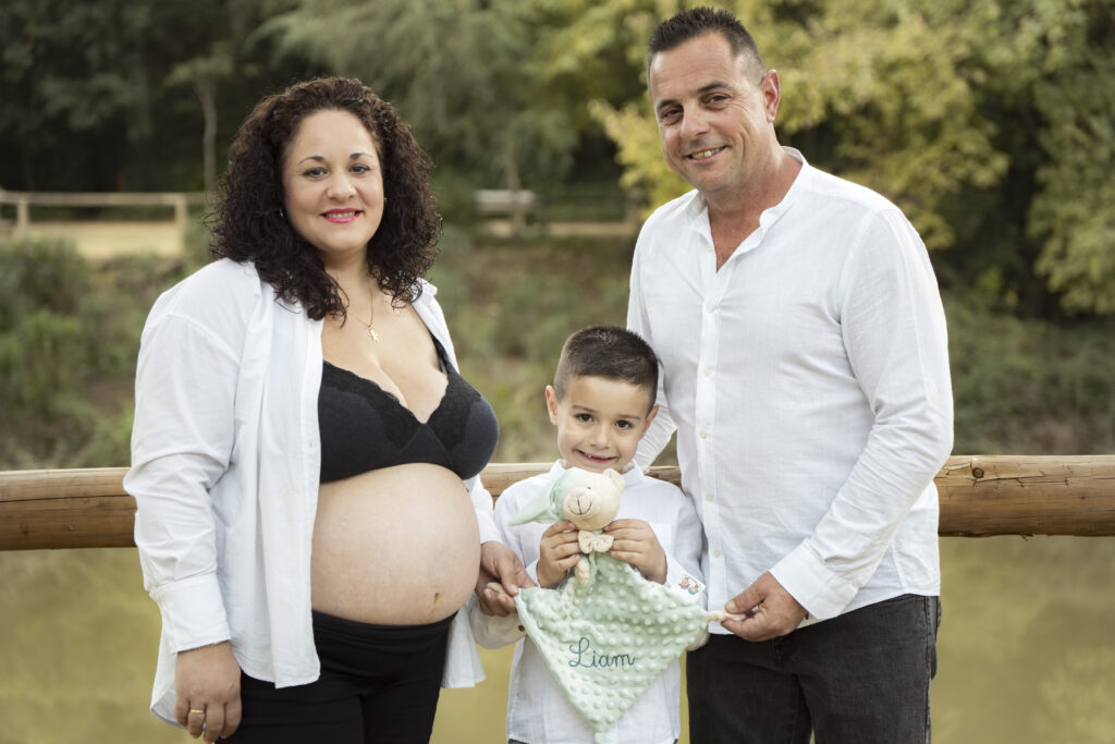 Familia posando al aire libre en sesión de embarazo.