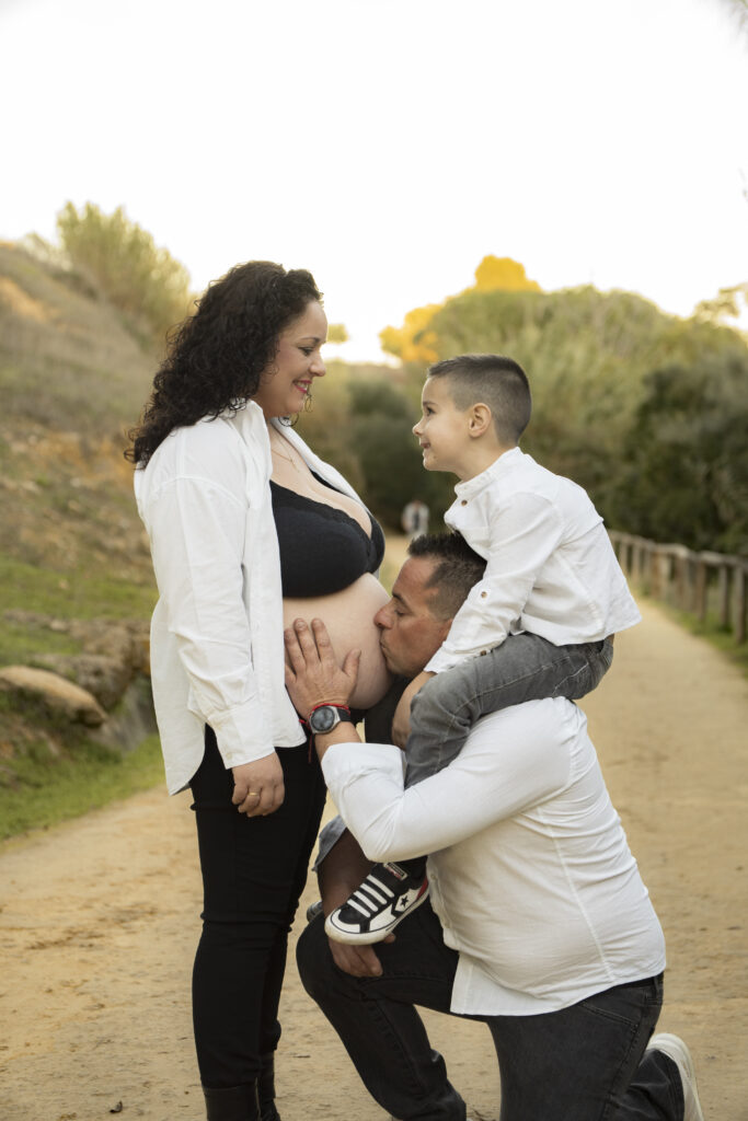 familia besando a mamá al aire libre.